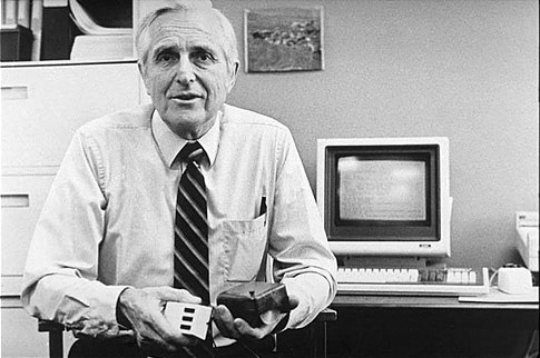 Douglas Engelbart con el ratón original en sus manos
