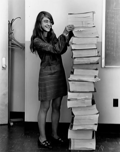 Margaret de pie frente a los listados del software de vuelo del módulo lunar y del módulo de mando del Apollo, en 1969